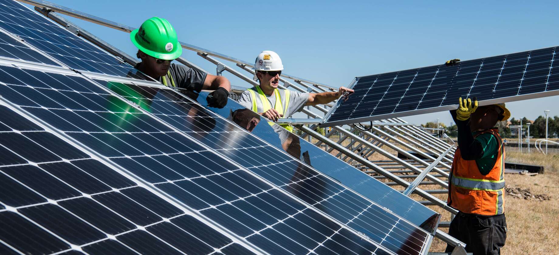 men holding solar panels above head